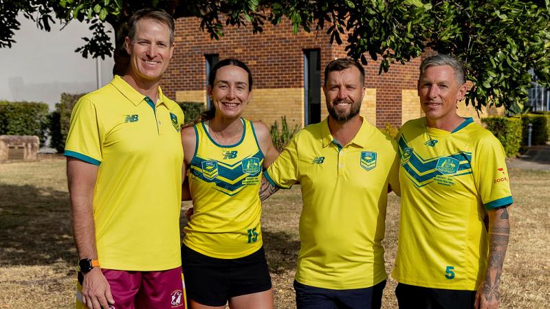 Four people in yellow and green sports outfits stand together outdoors.