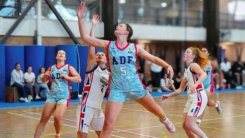 An Australian Defence Force basketballer stretches out and shoots a hoop.