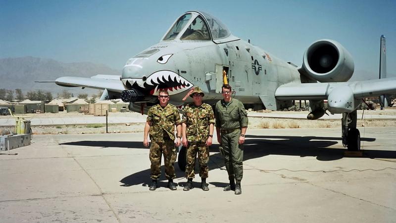 Three men in uniform stand in front of an aircraft.