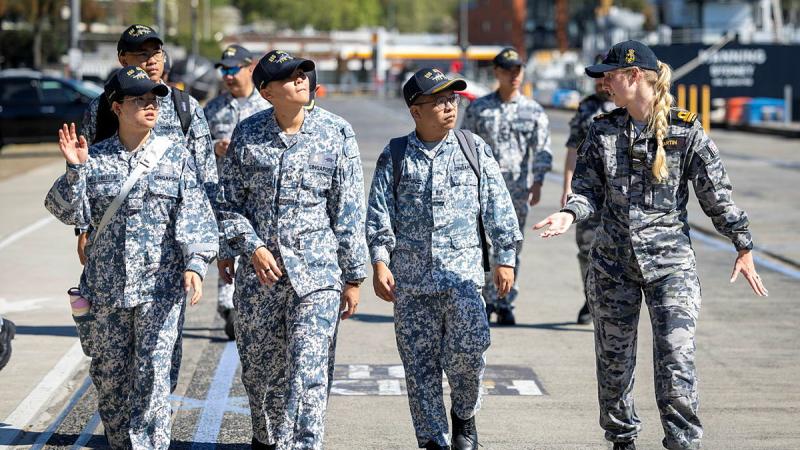A small group of people in two types of uniforms walk side by side while talking.