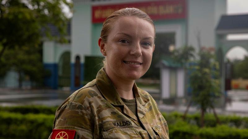 A woman in uniform with a red patch on her shoulder.