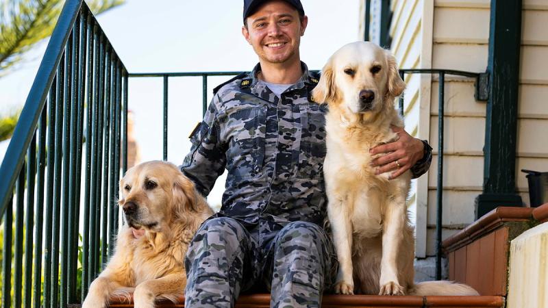 A man hugs two dogs. 