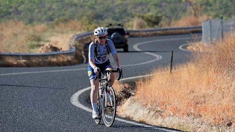 A woman in cycling gear riding a bike down an empty road.