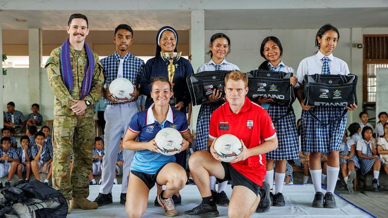 A group of students, civilians and military personnel with soccer equipment.
