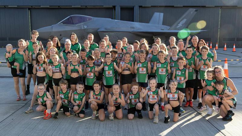 A large group of youth athletes and adults in matching athletic uniform.
