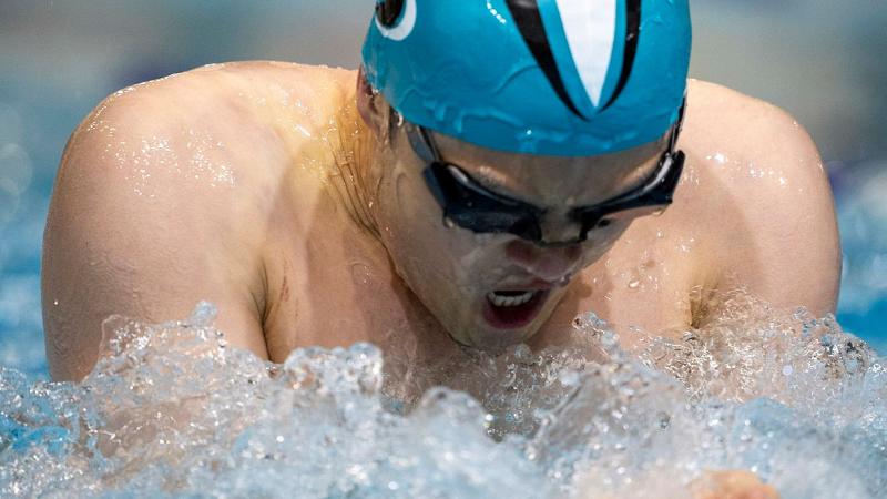 A man in a swimming cap and goggles swims.