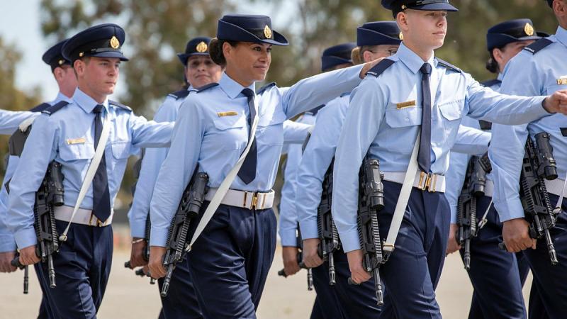 A group of men and women in military uniform march in formation.