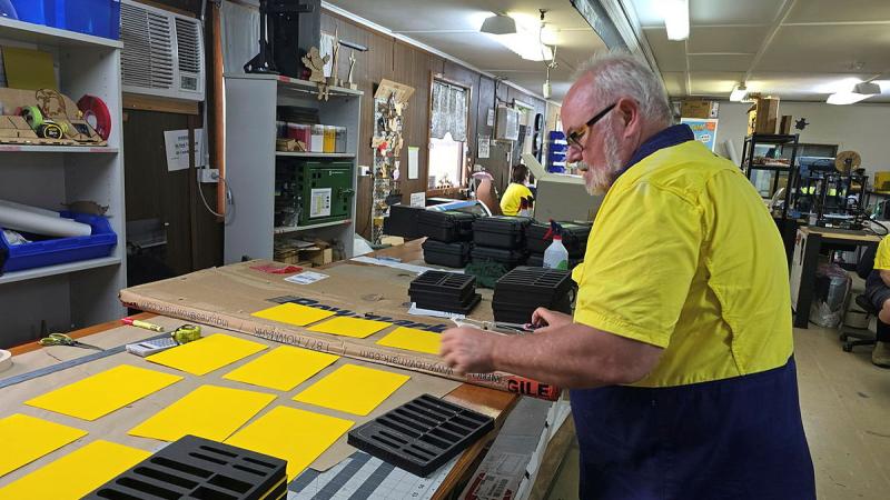 A man working at a desk in a factory-style setting.