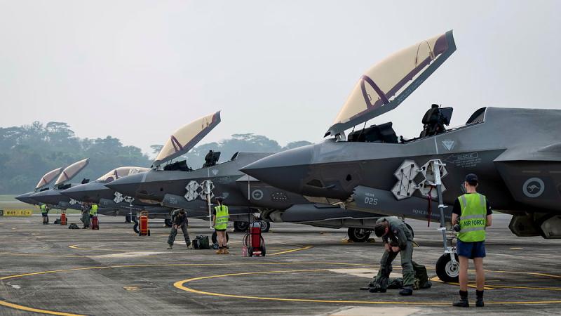 Several Air Force personnel in high-vis attend to four aircraft with their cockpits open.