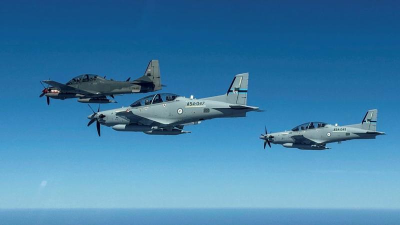 Three aircraft fly side by side in the sky above the ocean.