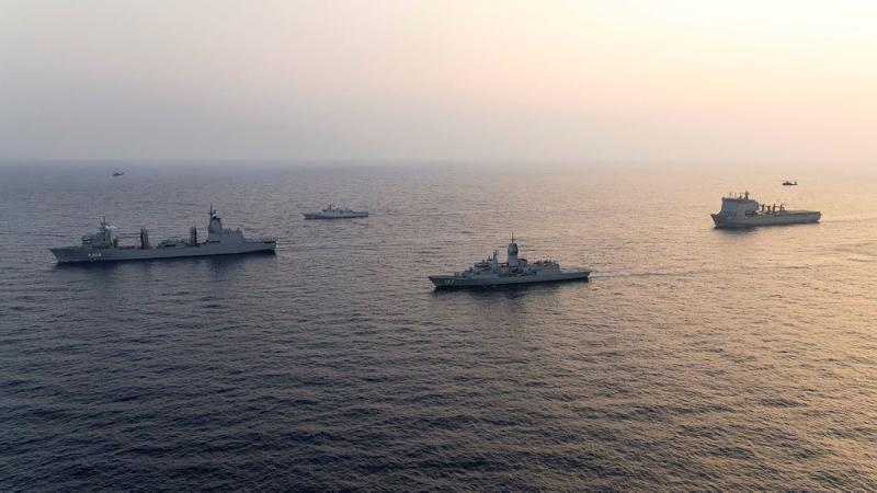 Four ships sail together in the ocean.