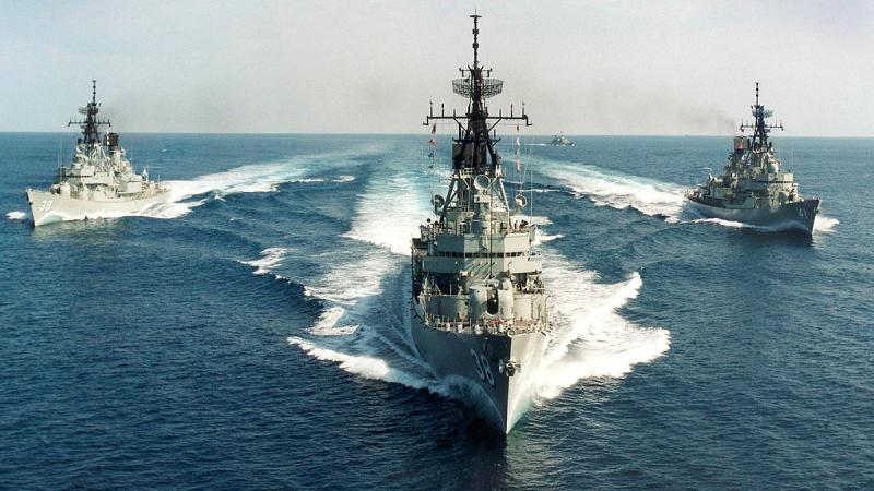 Three ships sailing in formation at sea.