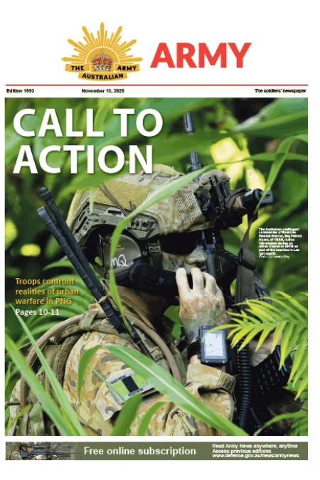 A soldier uses binoculars while concealed in dense vegetation during a training exercise.