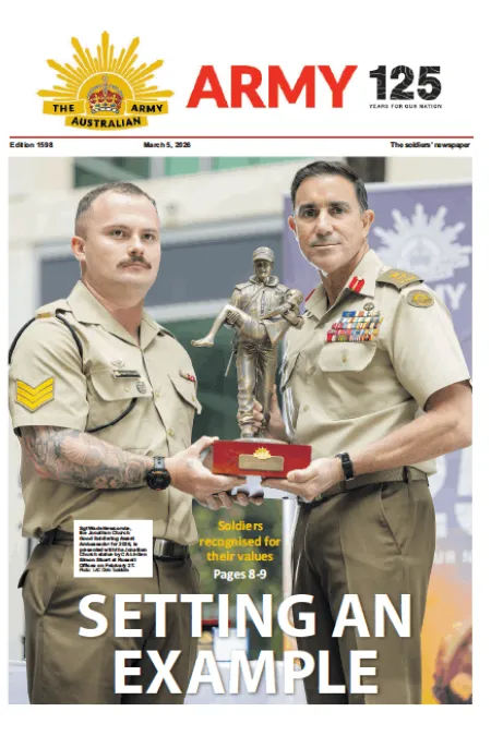 Two Australian Army personnel hold a military award trophy on the front page of Army newspaper.