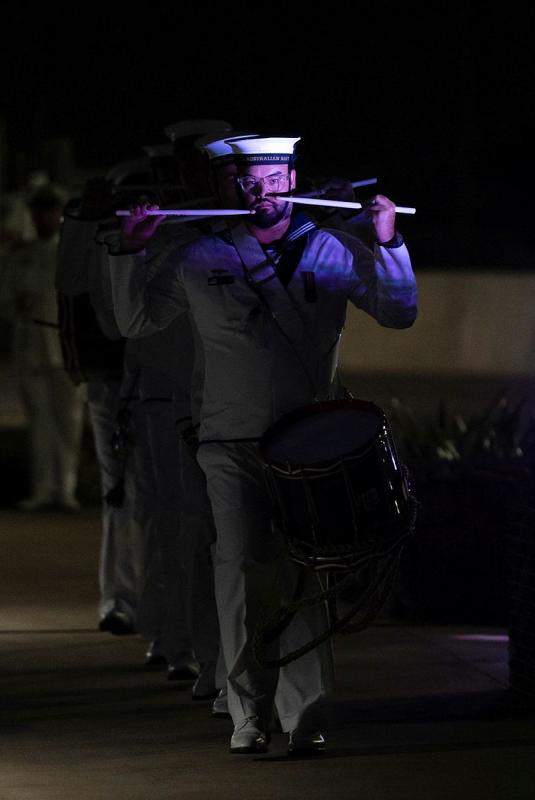 A Navy member holds his drumsticks up to his face during a parade.