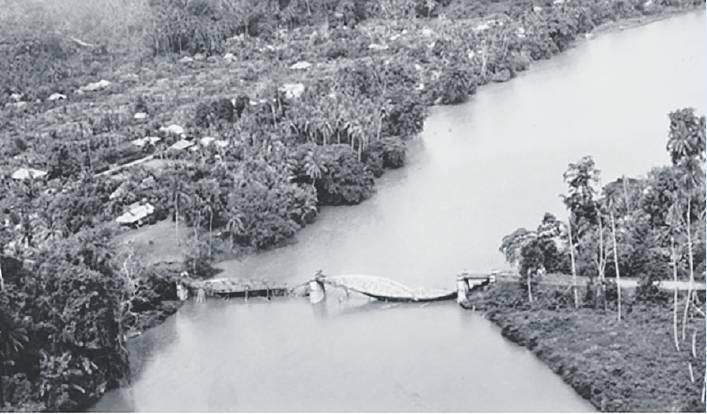Black-and-white aerial photograph of a wide river winding through a densely vegetated tropical landscape.