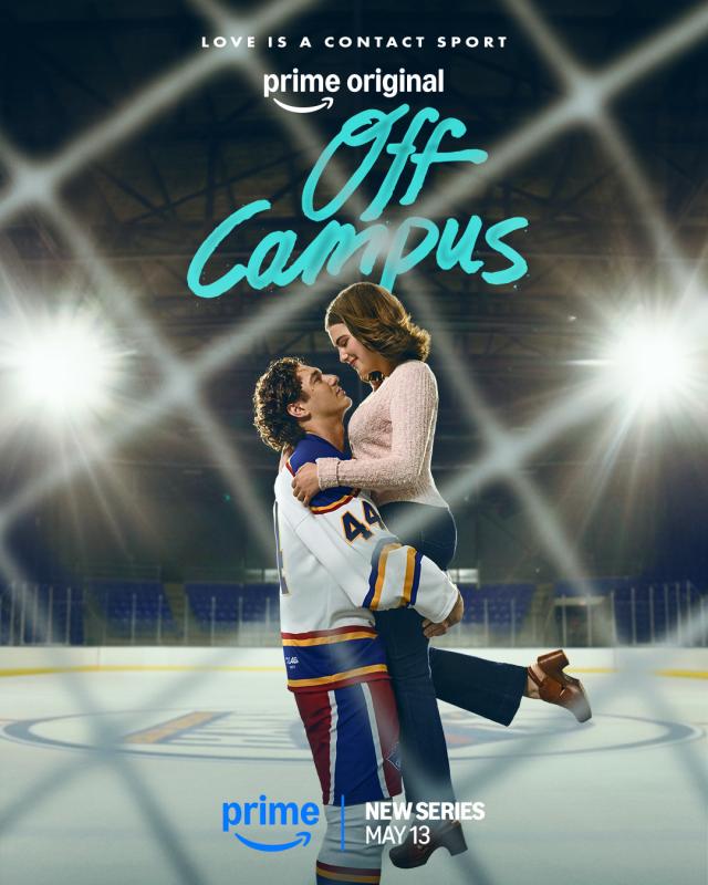Man lifts woman up against backdrop of an ice skating rink