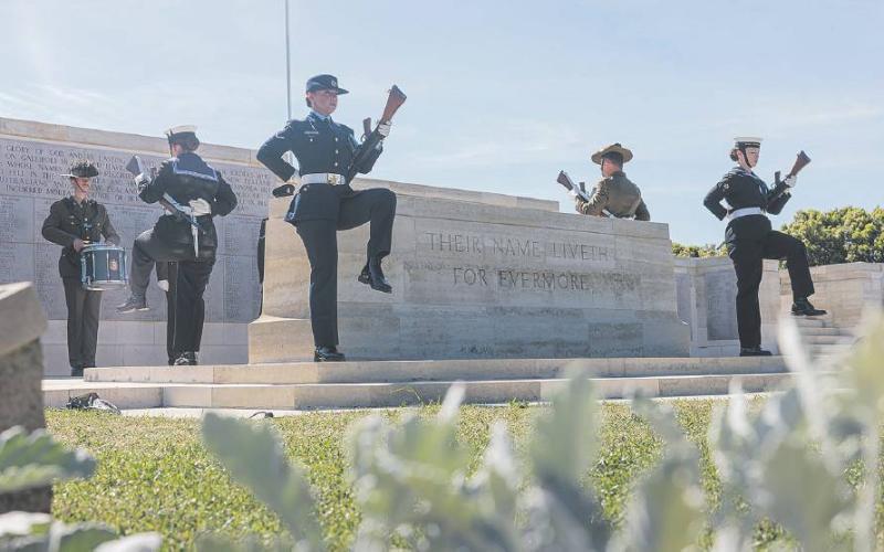 Military personnel marching at a memorial site.