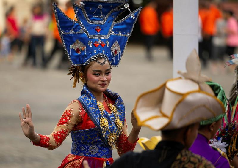 A female dancer in costume performs for a crowd of people.