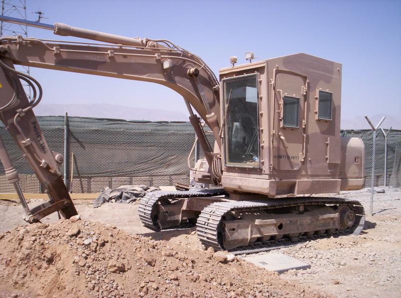 An excavator digs in the dirt of a fenced area.