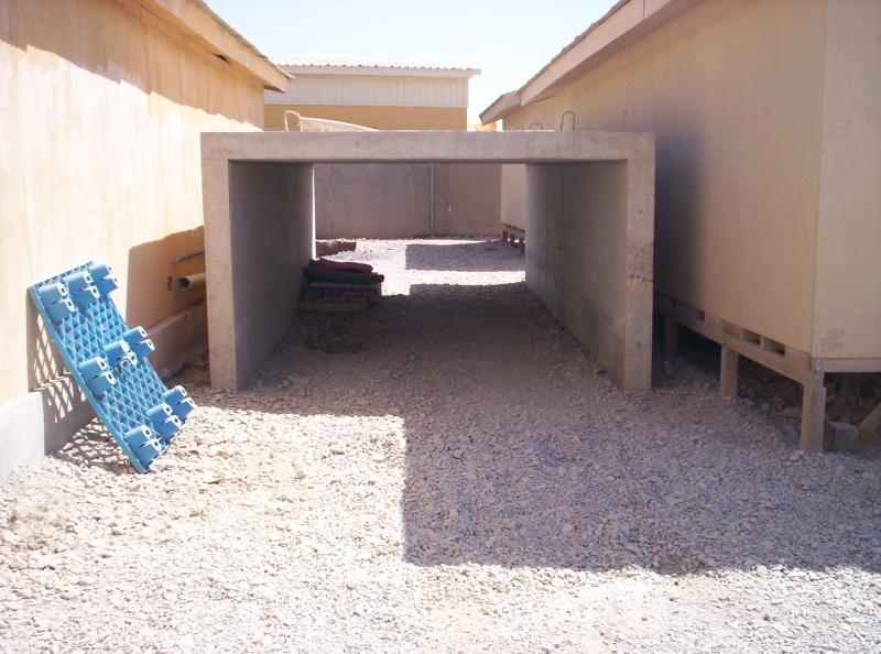 An open concrete shelter between two buildings.