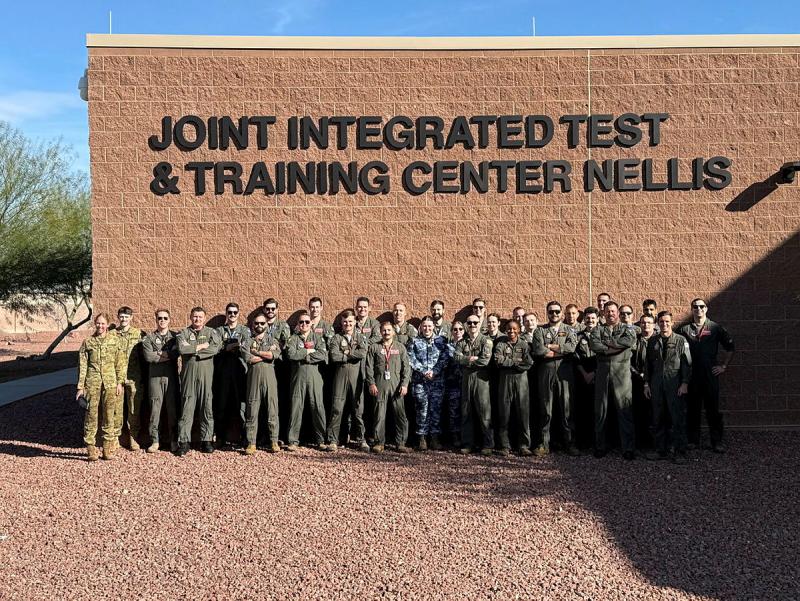 A group of military personnel standing in front of a wall at a training centre.