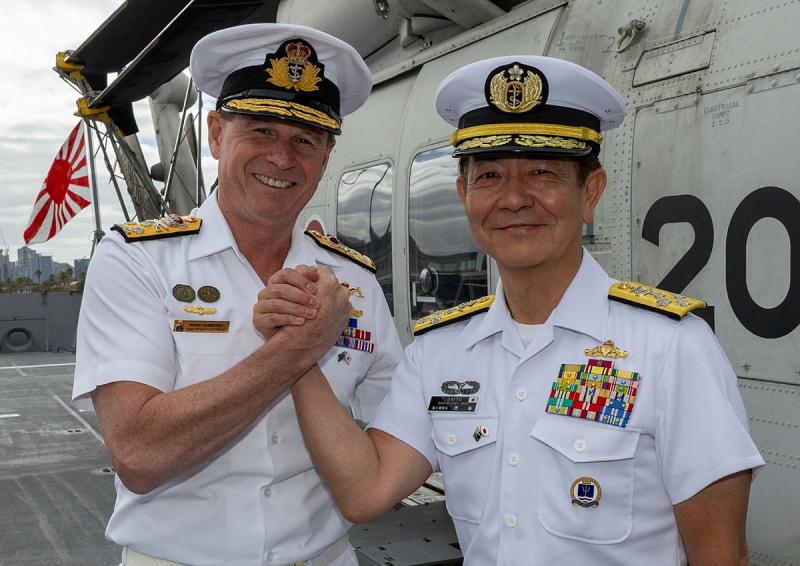 Australia's Chief of Navy locks hands with a Japanese naval chief on the deck of a ship.