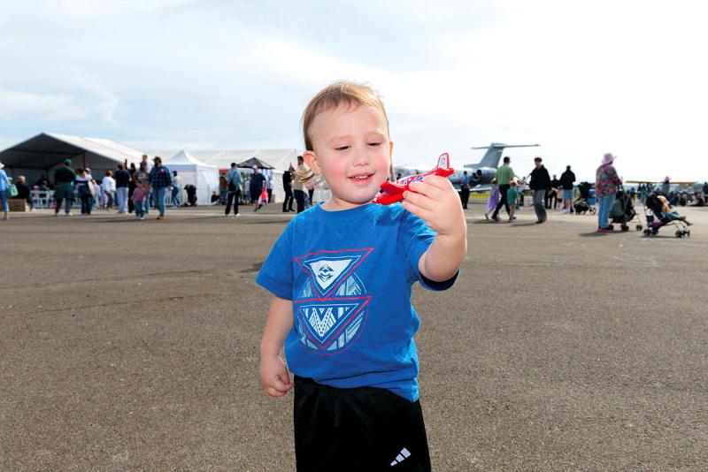 A toddler holding a small red aircraft.
