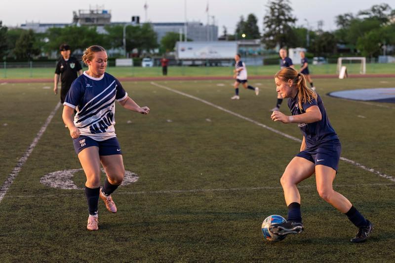 Two women play football.
