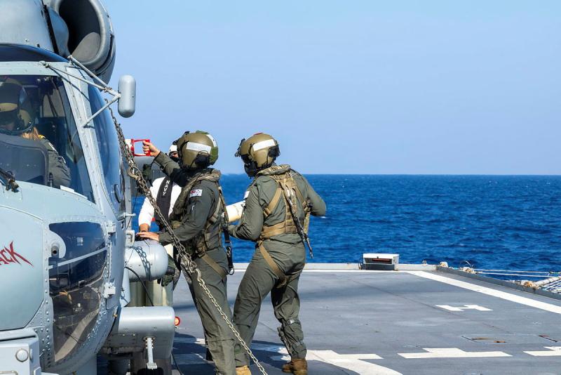 Two military aircrew next to a helicopter.