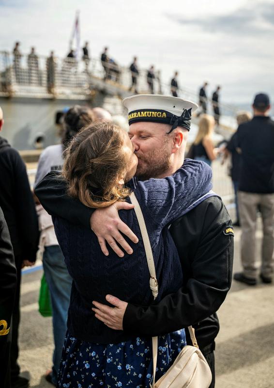 A woman kisses her sailor partner who has just returned from sea.