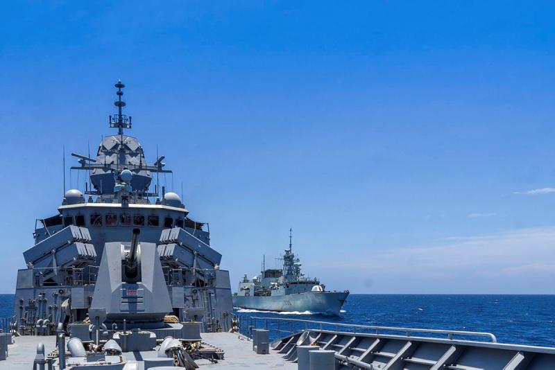 Two navy ships sail together at sea 