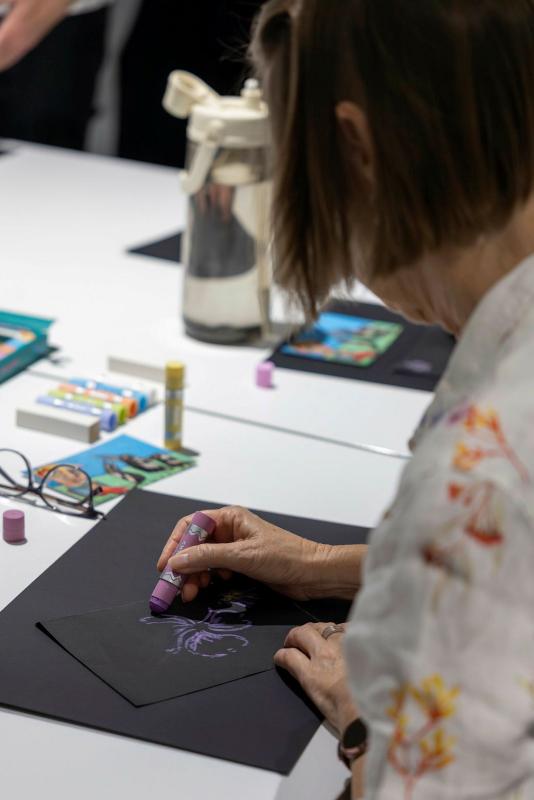 Royal Australian Air Force aviator Flight Sergeant Karen Tate-Smith draws with a paint stick during a workshop at the 2026 Defending the Arts exhibition at the Australian Defence Force Academy.