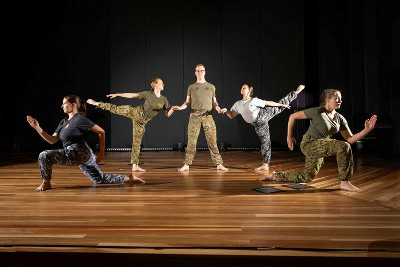 Five military personnel performing on stage.