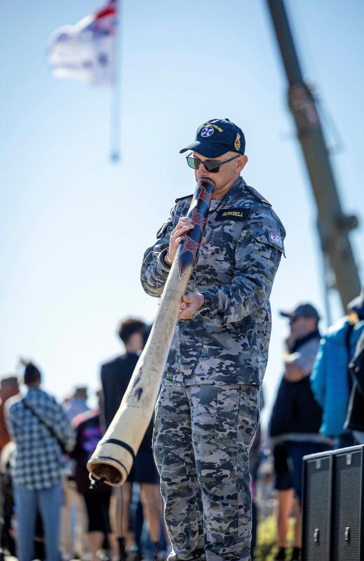 A sailor plays the didgeridoo.