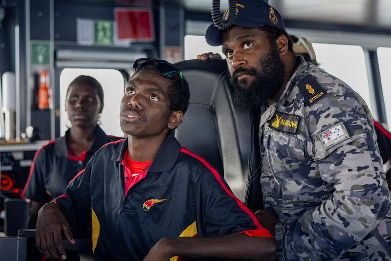 Two men look up into the distance from a ship.