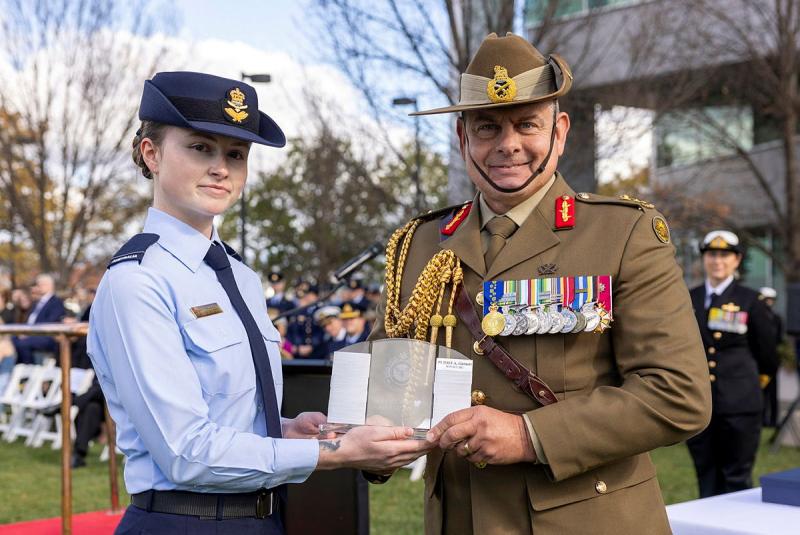 A military man hands over an award to an Air Force member. 