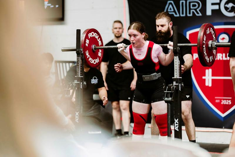 A woman prepares to lift a weighted bar.