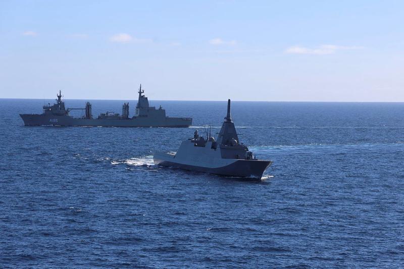Two ships sail together at sea.