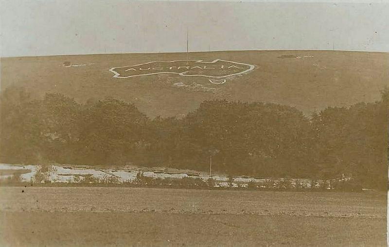 A sepia photo of a chalk map of Australia cut into a hillside with tents in the foreground.
