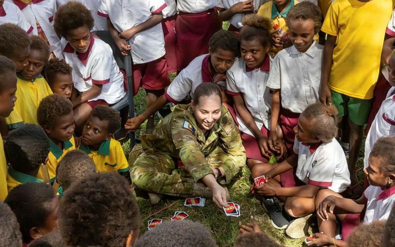 Australian Army soldier, Sergeant Breianon Young, playing a card game with school children as part of Operation Render Safe community engagement at St Joseph's Bitipaka Primary School in Kokopo, Papua New Guinea.