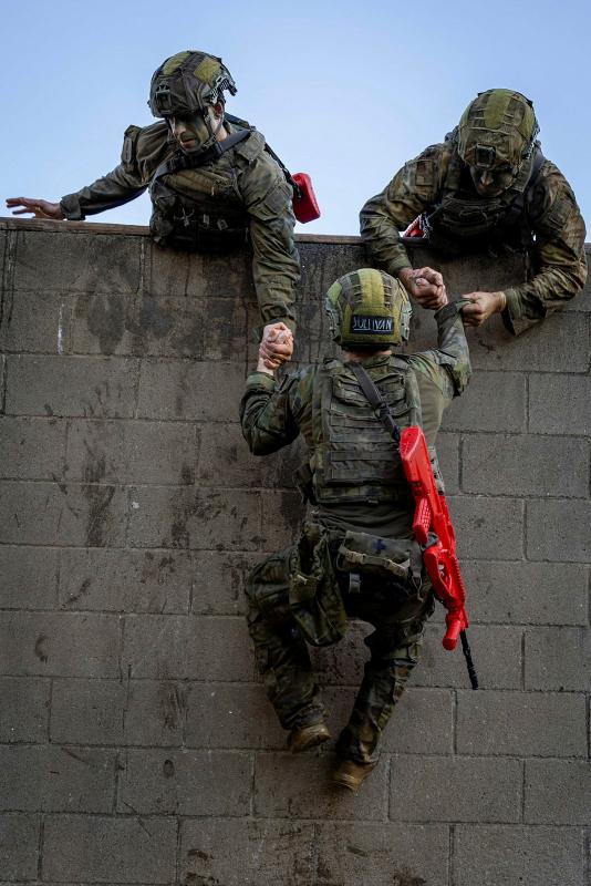 Australian Army trainees from the School of Infantry haul a member of their section over the high wall obstacle during Exercise HardCorps to complete their Riflemen's course at Singleton Military Area, NSW.