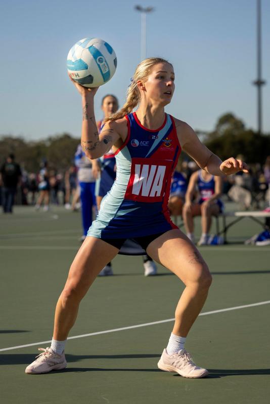 A woman aims to throw a ball while playing netball.