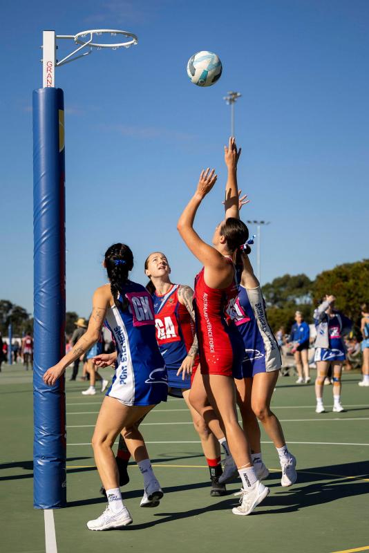 A netball player throws the ball into the goal.