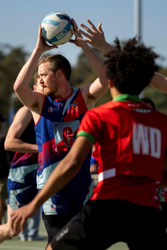 A man looks to throw the ball during a game of netball.