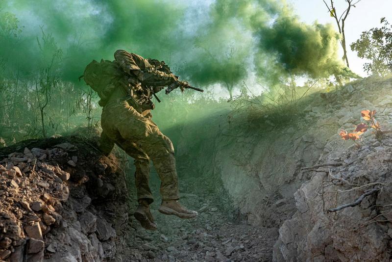 An Australian Army soldier from Bravo Company, 5th/7th Battalion, Royal Australian Regiment, jumps into a trench through green smoke during a combined arms live-fire assault on a trench system as part of Exercise Predator’s Walk at Mount Bundey Training Area, Northern Territory, 7 June 2026.