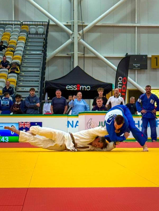 Two judo competitors wrestling on a mat.