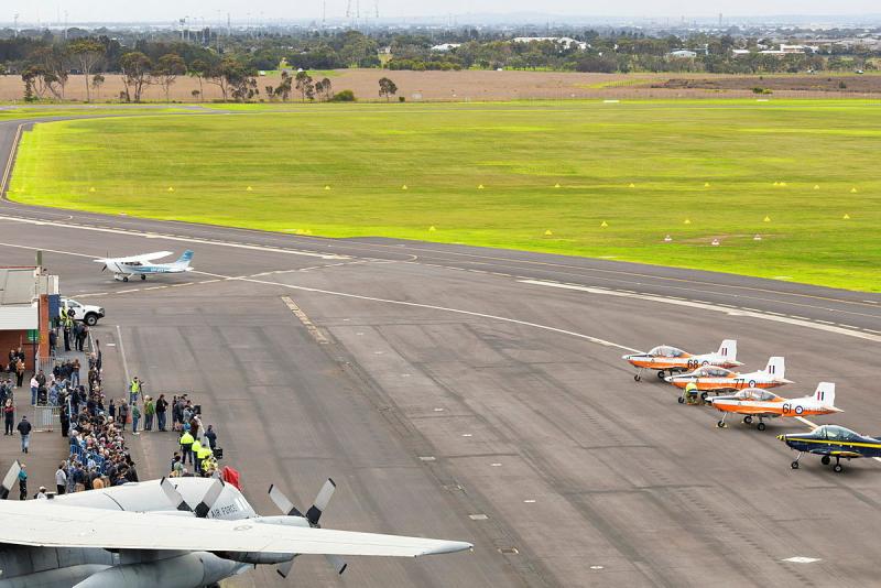 Bird's-eye view of people and aircraft on the tarmac at a small airport.