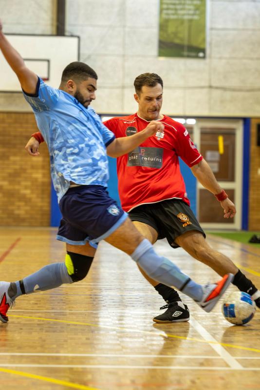 Two male players compete in a game of futsal.