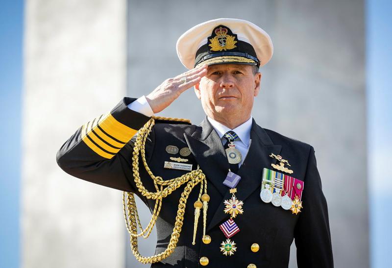A decorated military man salutes.